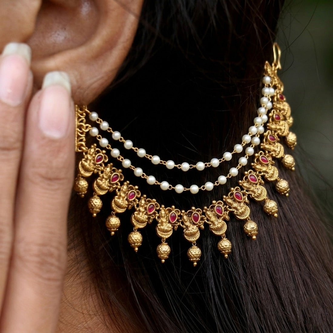 Elegant gold ear chains with pearls and red gemstones, showcasing unique craftsmanship and style.