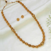 Antique Gold-Plated Beaded Long Necklace Set with textured beads and matching earrings on a white background.