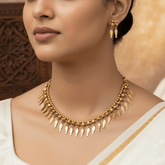 Antique Elakkathali Necklace with Earrings displayed by a model, featuring golden leaf-shaped charms and matching earrings.