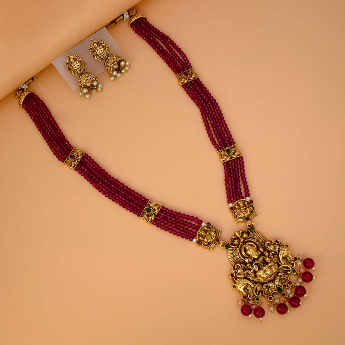 Antique Gold Lakshmi Pendant Beaded Long Necklace Set with matching jhumka earrings in Dark Red.