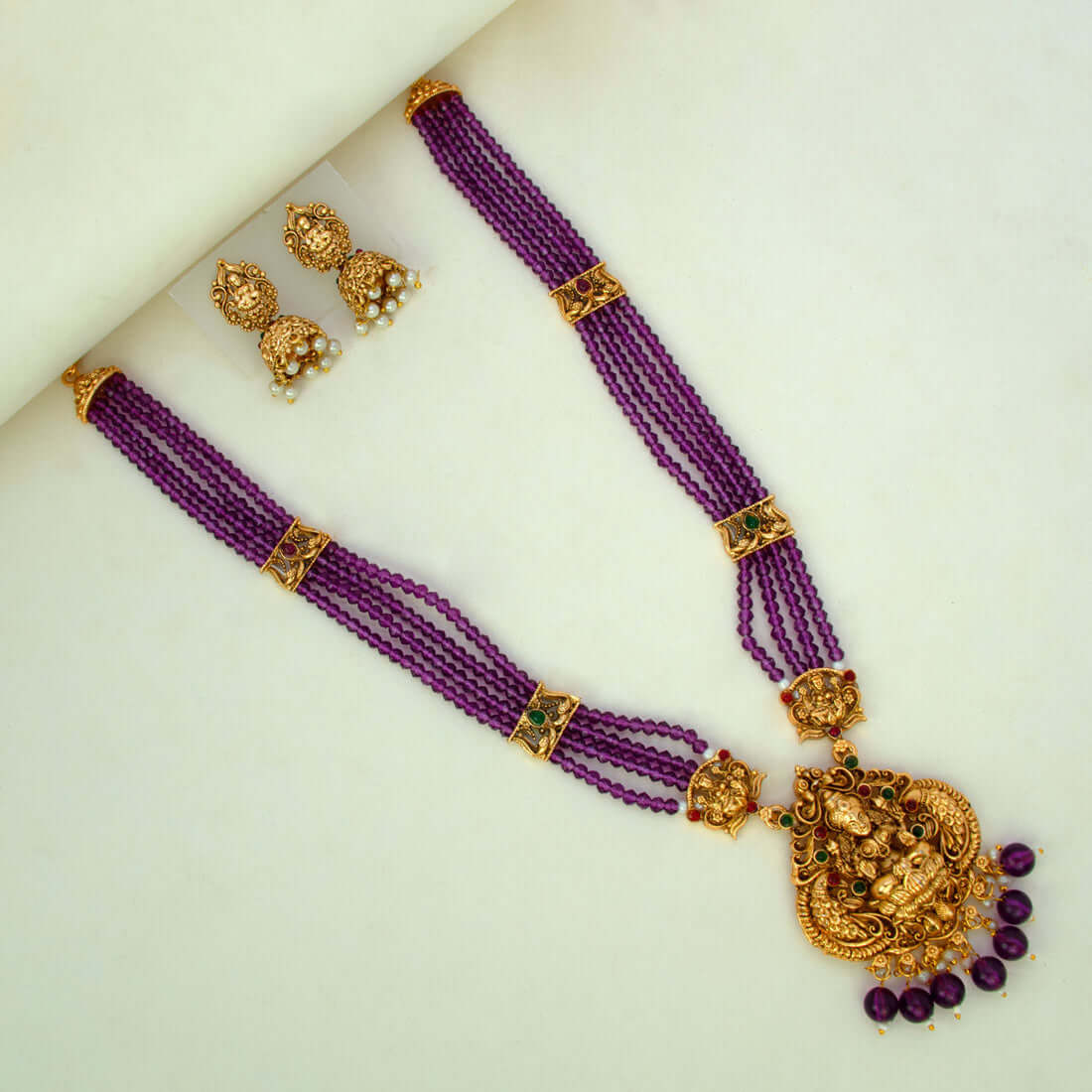 Antique Gold Lakshmi Pendant Beaded Long Necklace Set with purple beads and jhumka earrings.