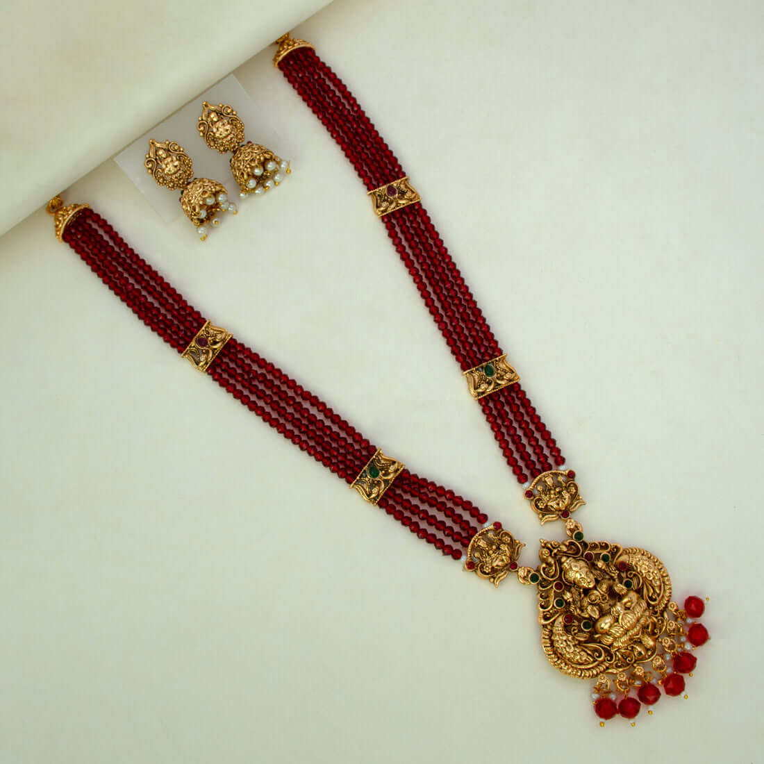 Antique Gold Lakshmi Pendant Beaded Long Necklace Set with red beads and matching jhumka earrings.
