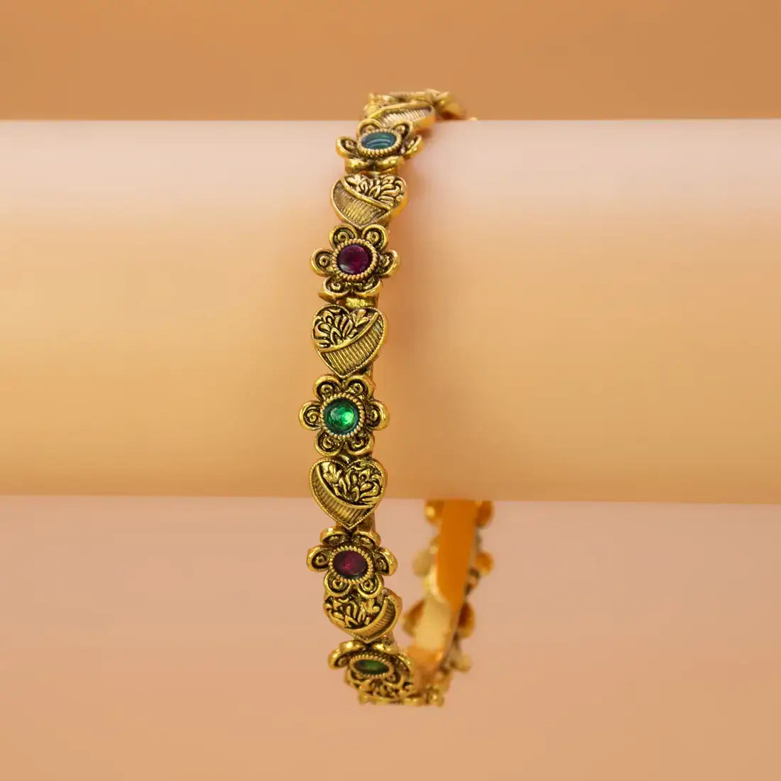 Antique Heart Floral Kemp Stone Victorian Bangle displayed on a wrist, featuring intricate gold design with colorful stones.