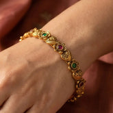 Heart Floral Kemp Stone Bangle worn on a hand, showcasing intricate gold design and colorful stones.