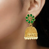 Gold earring with green gemstones worn by a model