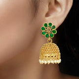 Gold earring with green gemstones worn by a model