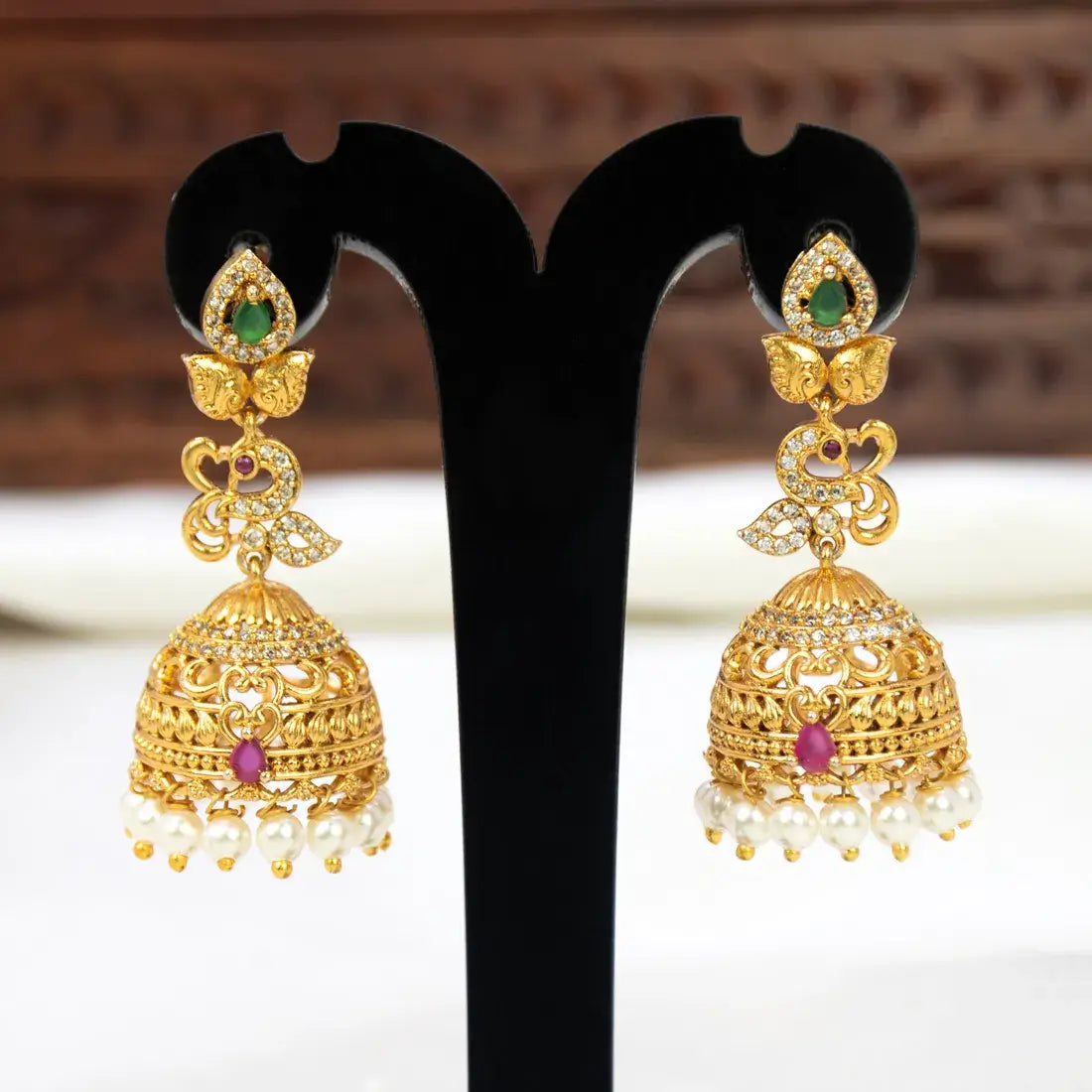Antique Multi Stone Peacock Jhumka Earrings featuring intricate designs and pearl drops on a display stand.