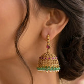 Antique Gold Ruby Red Kemp Stone Jhumka Earrings featuring green crystals and intricate detailing.