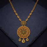 An ornate Antique Gold Big Floral Heart Pendant Long Necklace with a large filigree pendant and three teardrop charms, accented with small green stones, displayed on a dark slate surface.