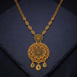 An ornate Antique Gold Big Floral Heart Pendant Long Necklace with a large filigree pendant and three teardrop charms, accented with small green stones, displayed on a dark slate surface.