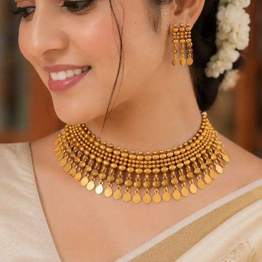 Antique Gold Beaded Elakkathali Necklace Set worn by a woman, showcasing intricate beadwork and matching earrings.