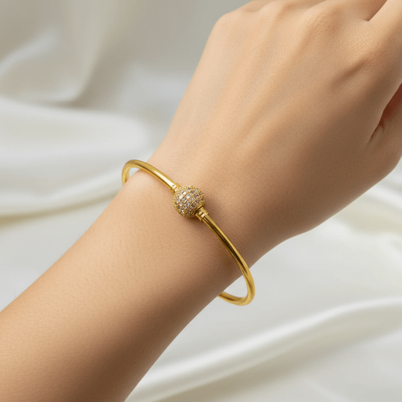 Charming Gold-Plated White CZ Stone Ball Bangle worn on a hand against elegant fabric.