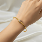 Charming Gold-Plated White CZ Stone Ball Bangle worn on a hand against elegant fabric.