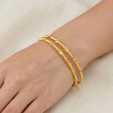 A hand wearing three Casual Gold Plated MC Mayoori Bangles with a textured surface.