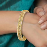 Close-up of hands with a gold bracelet against a teal fabric background