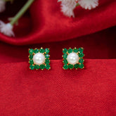 Gold-Plated Square Stone Cluster Pearl Stud Earrings featuring emerald stones and a pearl center on red fabric