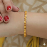 Delicate Gold Plated Wave Pattern Bangles worn on wrist, showcasing elegant wave design and lustrous finish.