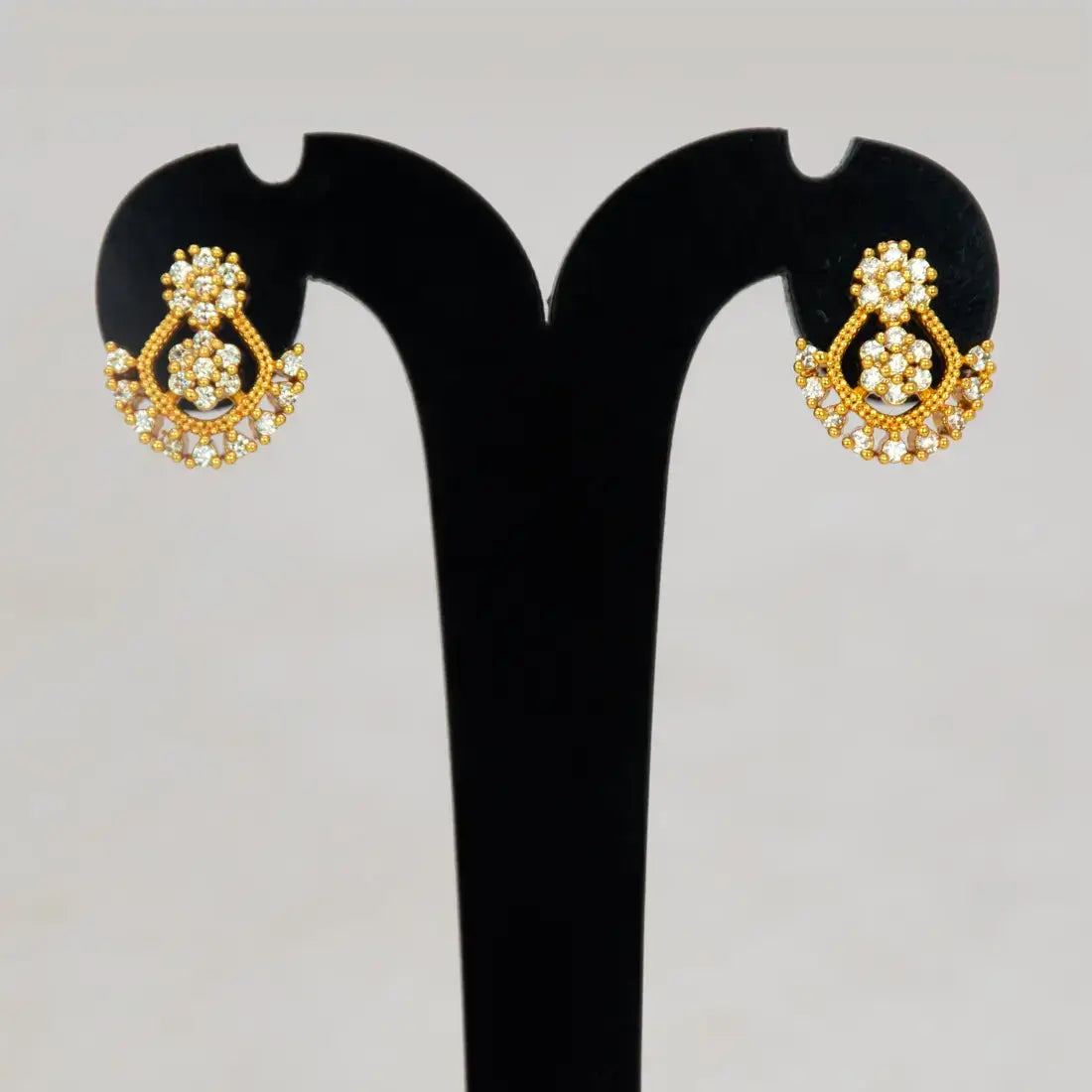 Dual Floral Design Gold Plated CZ Stone Stud Earrings displayed on earring stand with sparkling details.