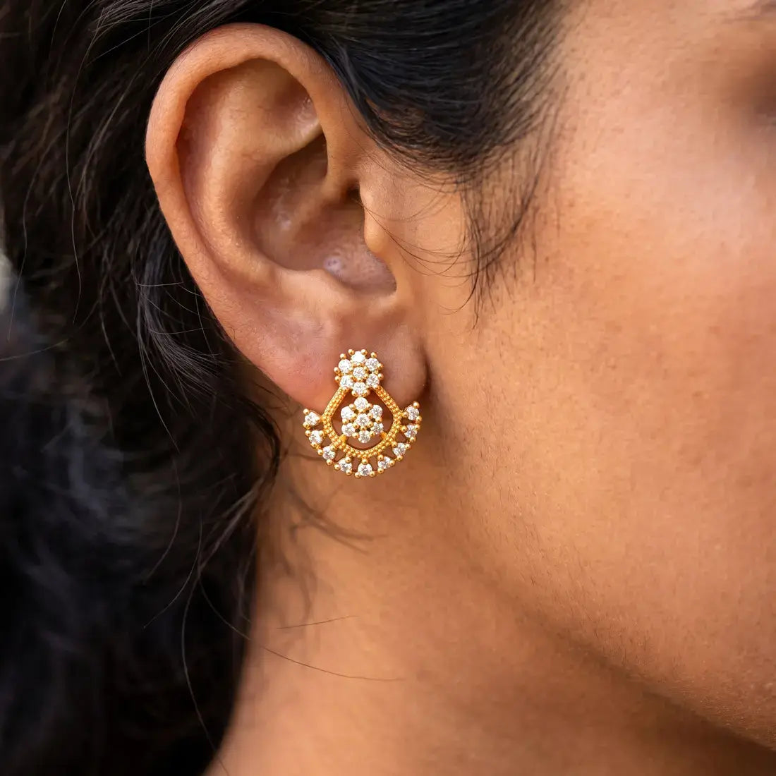 Dual Floral Design Gold Plated CZ Stone Stud Earrings worn on an ear, showcasing their intricate design and sparkle.