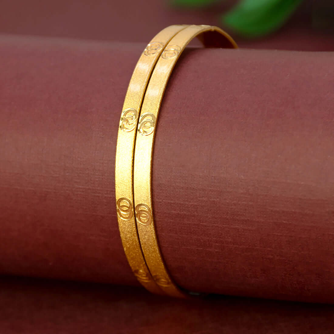 Elegant Matte Gold Plated Designer Bangles on a display surface, showcasing their smooth finish and elegance.