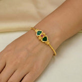 Elegant Gold-Plated Double Palakka Bangle for Women worn on a hand with green motifs and ruby stone accents.