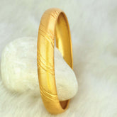 Gold Plated Medium Designer Lightweight Pipe Bangle with textured design on a stone background.