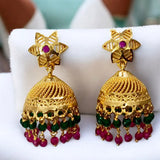 Gold earrings with red and green beads on a white cushion