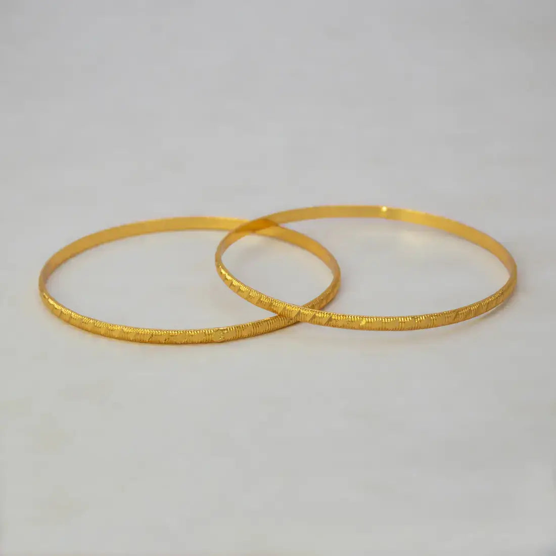 Lightweight Gold Plated Indian Bangles for Women displayed on a neutral background, featuring simple diamond-cut designs.