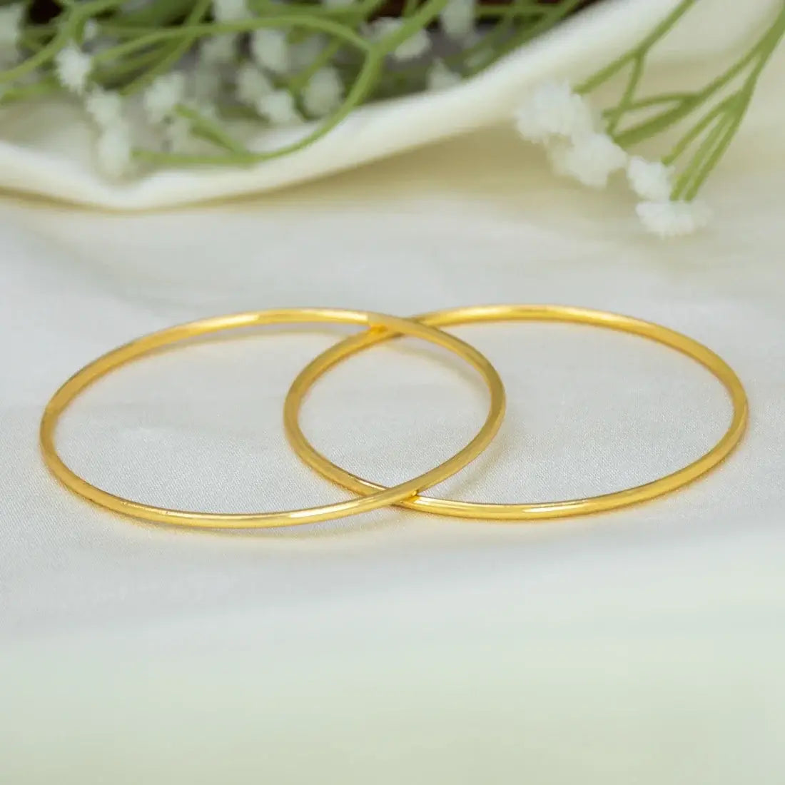 Gold-Plated Dailywear Thin Plain Bangles on soft fabric with delicate flowers in the background.