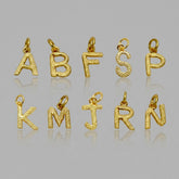 Gold letter pendants on a reflective gray surface