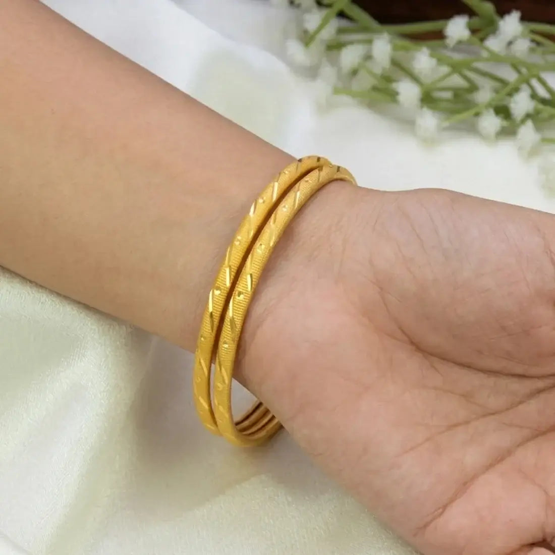 Gold-plated MC Textured Pipe Bangles elegantly displayed on a woman's wrist, showcasing refined textured detailing and a rich gold finish.