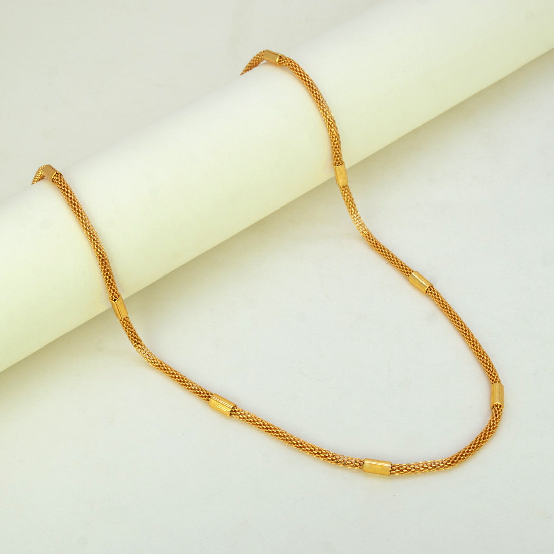 Elegant Gold Plated Mesh Pipe Chain displayed elegantly on a smooth surface, highlighting its delicate design and cylindrical accents.