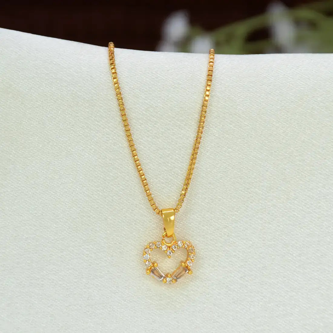 A gold box chain with a Gold-Plated CZ Heart Pendant Charm adorned with small clear stones and a central clear crystal, displayed on a white jewelry bust.