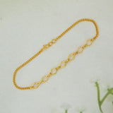 A delicate Gold-Plated Designer Chain Bracelet for Girls with elongated, textured oval links, displayed on a light off-white textured surface.