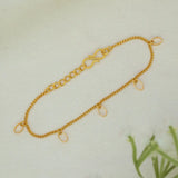 A delicate Gold-Plated Oval Hanging Chain Bracelet with three small oval dangling charms, laid flat on a light textured background.