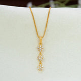 A gold chain necklace with a vertical Gold-Plated Three-tier Stone Floral Drop Pendant featuring three small flower clusters of cz stones, displayed on a white jewelry stand.