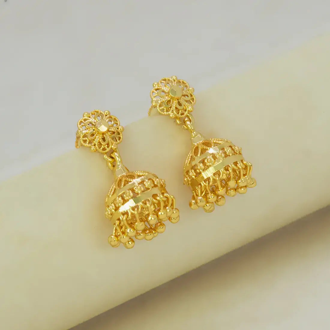 Gold earrings on a mannequin arm with a neutral background