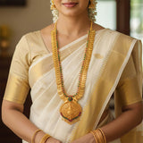 Gold Plated Ruby Emerald Lakshmi Kasu Haram With Pendant worn by a woman in a traditional saree.