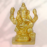 Gold-colored statue of a ganapathy on a light pink background