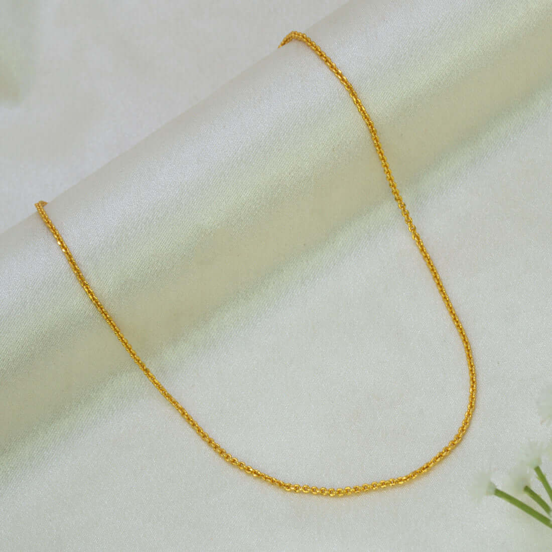 A Gold Plated Cutting Design Baby Chain necklace draped in a U-shape over a soft, off-white textured fabric background.