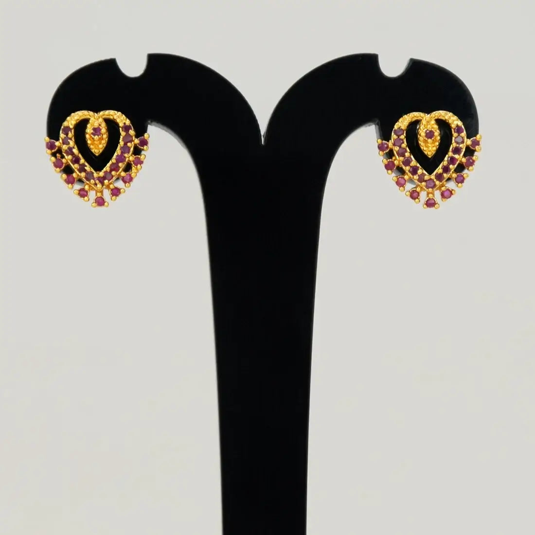 Dazzling Gold Plated Stone Heart Stud Earrings showcased on a display stand with intricate design and sparkling stones.