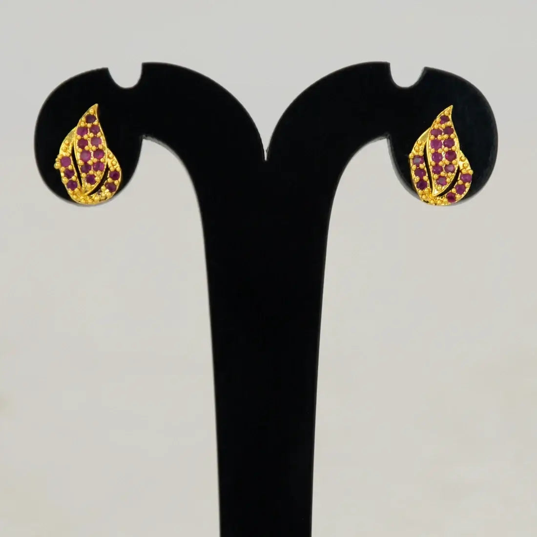 Gold Plated Leaf Model Stone Stud Earrings showcasing vibrant Ruby/CZ stones in an elegant leaf design.