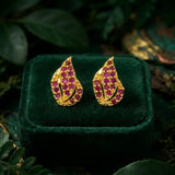 Gold Plated Leaf Model Stone Stud Earrings featuring vibrant Ruby stones on a green velvet display.