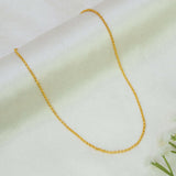A Gold Plated Rolo Baby Chain for Kids & Petite Adults draped in a U-shape on a soft, light cream-colored fabric background with a small white flower in the corner.