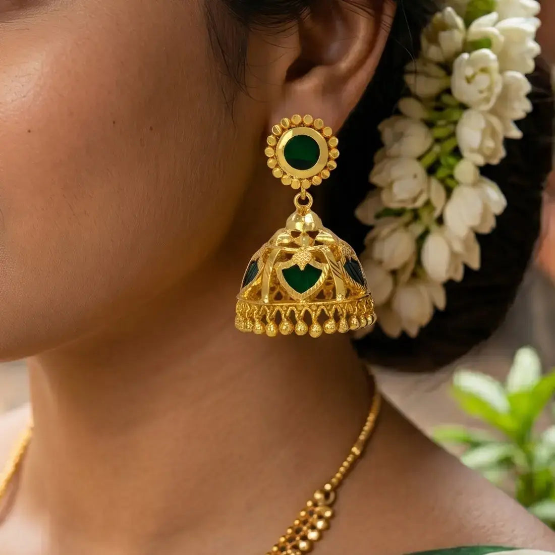 Elegant close-up of Green Palakka Jhumka Earrings featuring gold-tone design and green stones.