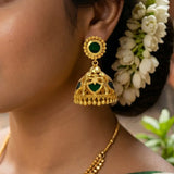Elegant close-up of Green Palakka Jhumka Earrings featuring gold-tone design and green stones.