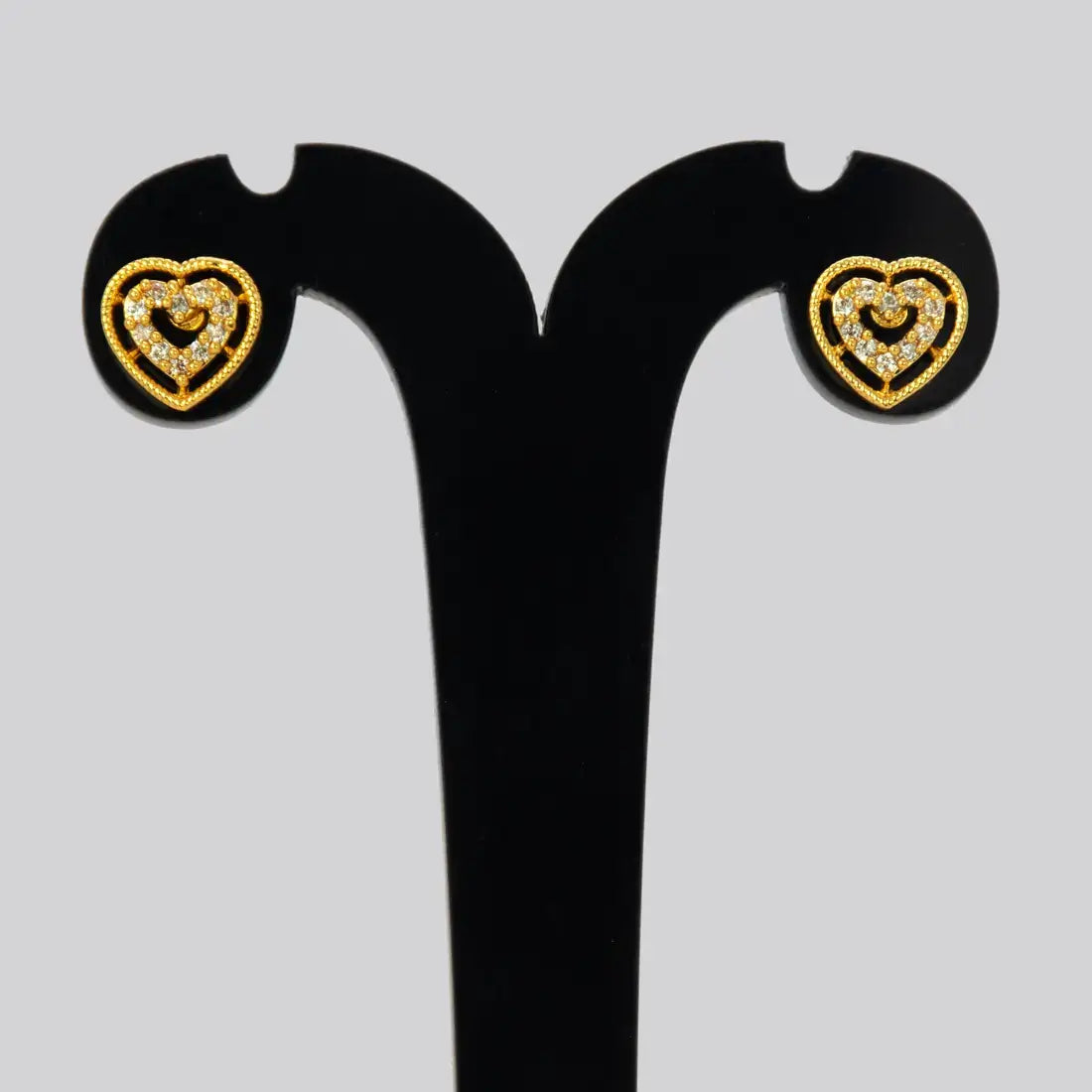 Gold Heart Design Stone Stud Earrings showcasing intricate heart-shaped designs with sparkling stones on a black display.