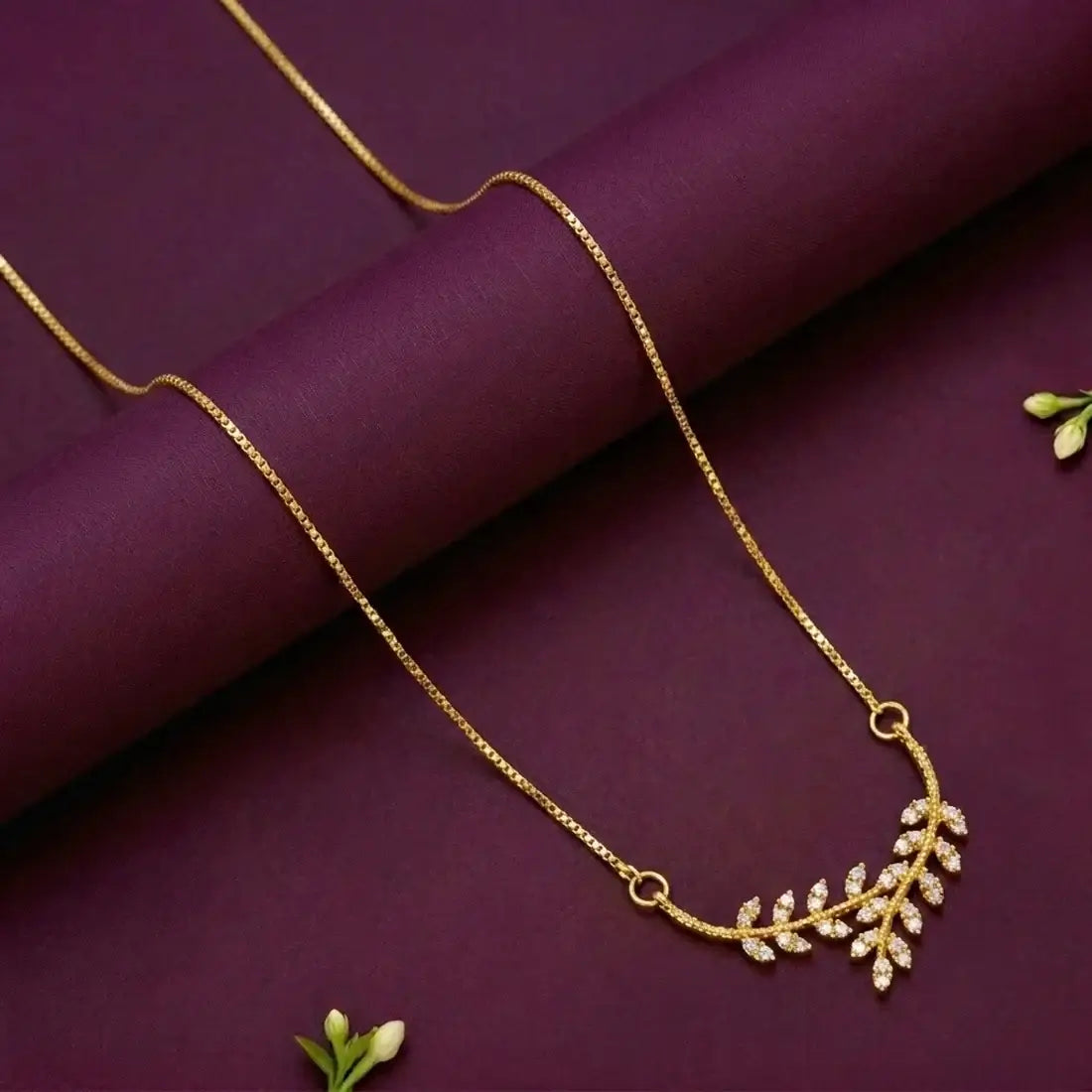 Gold Plated American Diamond Leaf Pendant Necklace displayed on a dark surface with elegant design and cubic zirconia accents.