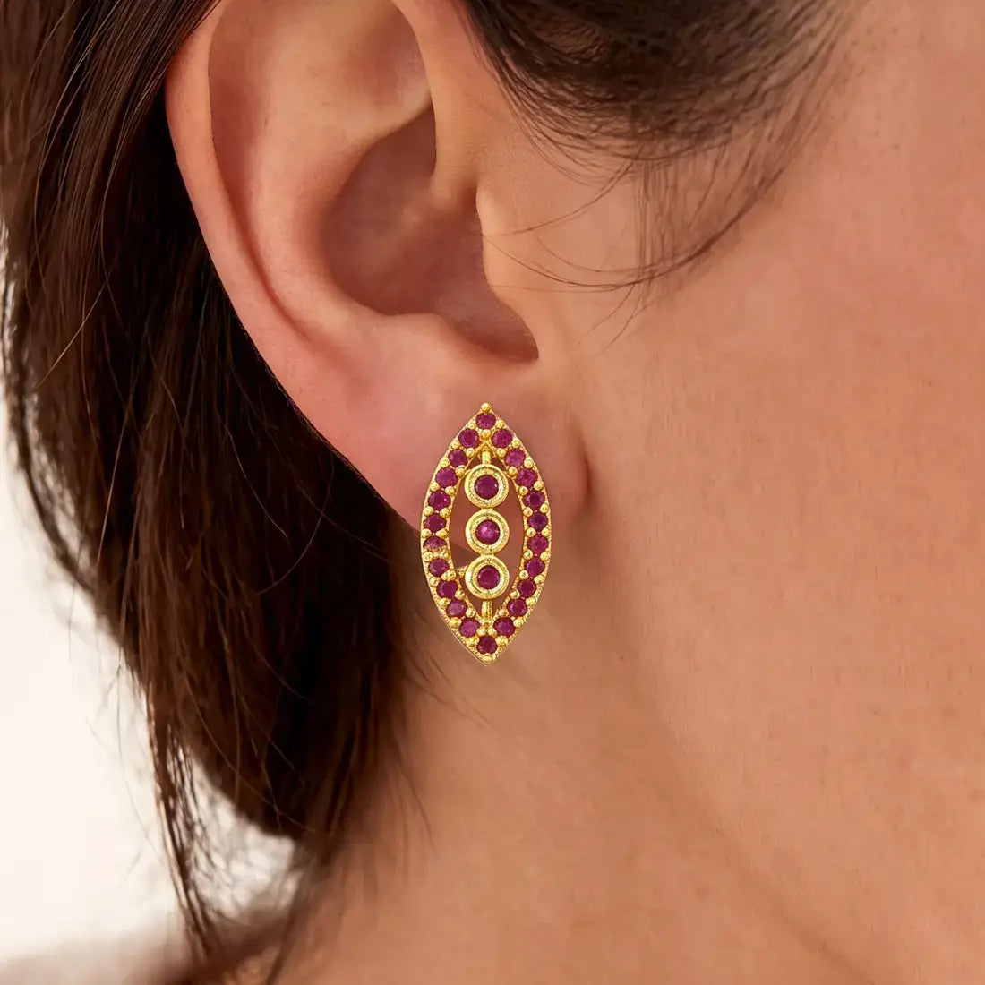 Marquise Ruby Stone Gold-plated Stud Earrings on model's ear, featuring synthetic ruby stones in classic design.