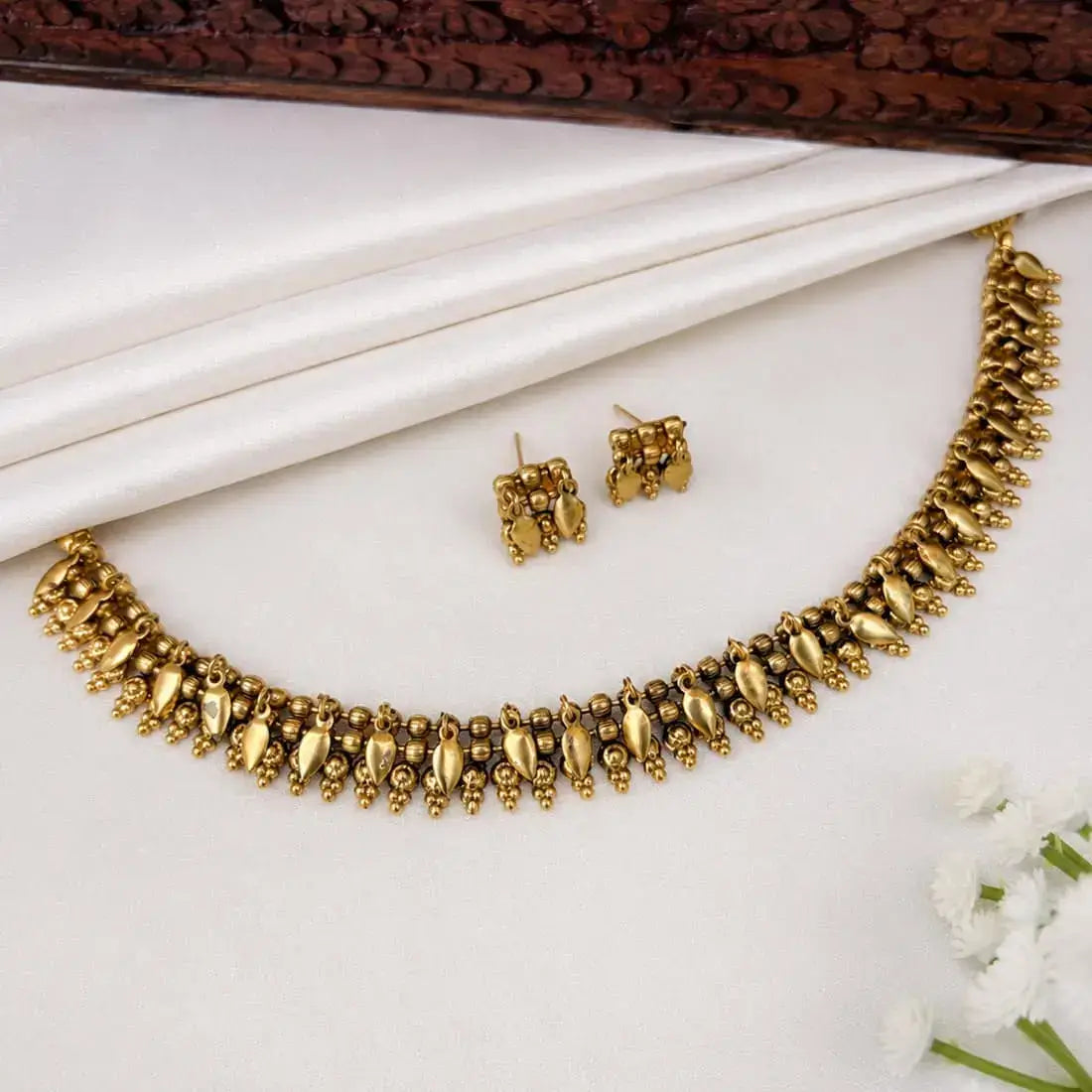 Antique Gold Beaded Elakkathali Choker Necklace Set with matching earrings displayed elegantly.